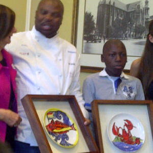 Lalela's Sakhi Sifuba hands over his hand painted creation to Masterchef SA's Benny Masekwameng